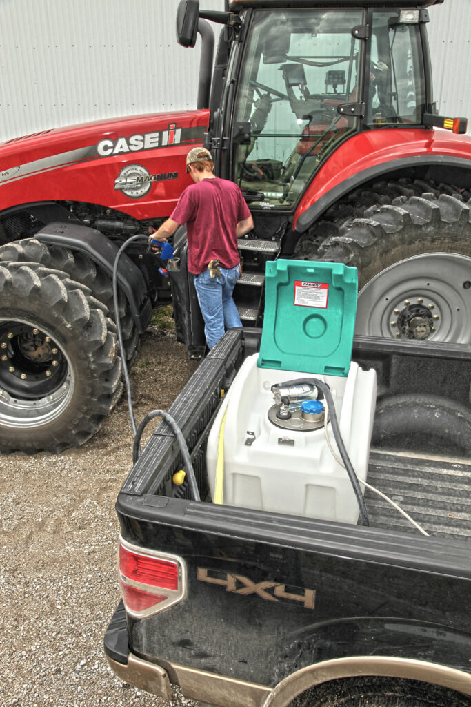 Image Showing an Enduraplas DEF Transfer Tank Being Used from the Back of a Pickup Truck to Refill a Tractor's Empty DEF Tank